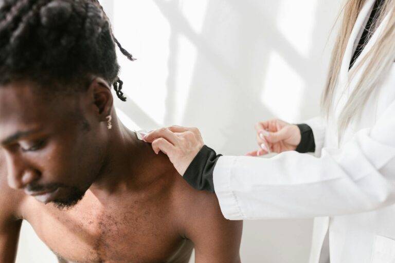 Close-up of a man receiving a shoulder massage for pain relief indoors.